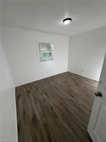 Unfurnished room featuring dark wood-type flooring and a textured ceiling