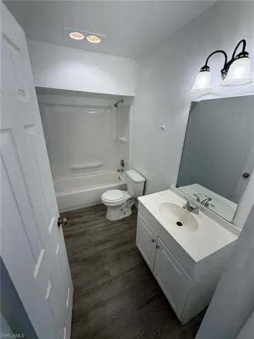 Bathroom featuring dark wood-style flooring, vanity, and shower / tub combination