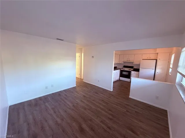 Kitchen featuring open floor plan, white appliances, dark wood-style floors, and under cabinet range hood