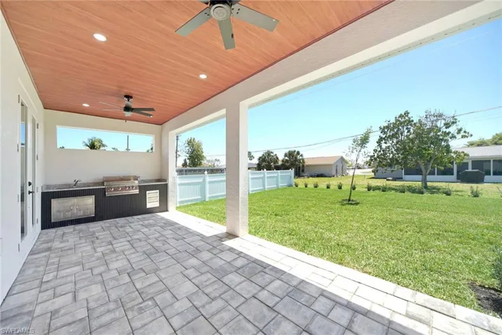 Fenced backyard featuring exterior kitchen, a patio, and a ceiling fan