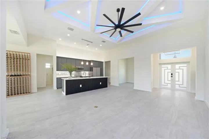 Unfurnished living room featuring a high ceiling, ceiling fan, coffered ceiling, recessed lighting, and beam ceiling
