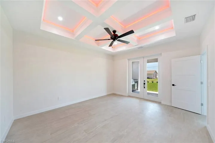 Empty room featuring french doors, coffered ceiling, ceiling fan, beam ceiling, and light flooring