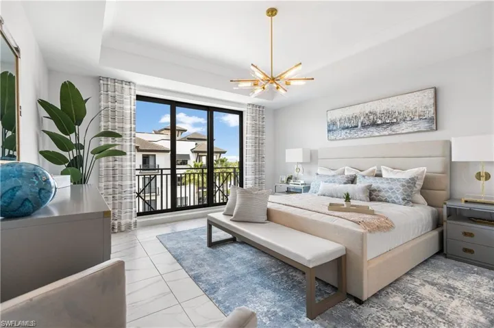 Bedroom featuring access to exterior, a tray ceiling, and a chandelier