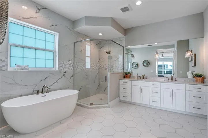 Master bath featuring double vanity, a soaking tub, a marble finish shower, and recessed lighting - Virtually Edited Image