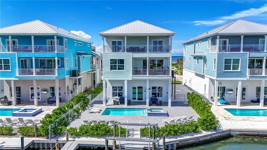 Back of property with a patio and a pool with connected hot tub - Virtually Edited Image