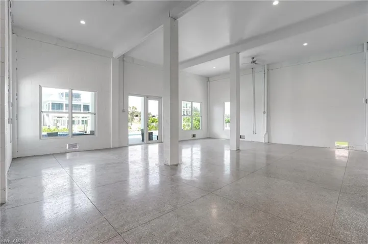 Pool and Game Room with high ceiling, speckle patterned floor, beam ceiling, concrete block wall, and ceiling fan - Virtually Edited Image