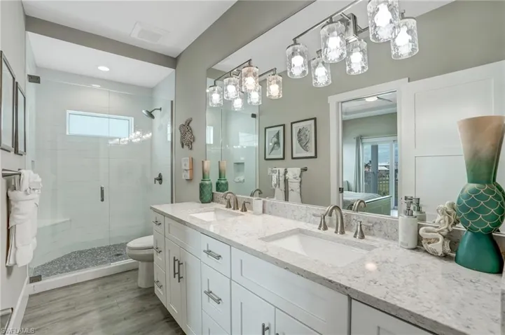 Bathroom with a shower stall, double vanity, and light wood-style flooring - Virtually Edited Image