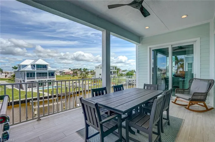 Wooden deck with a patio area, a water view, a ceiling fan, outdoor dining space, and a residential view - Virtually Edited Image
