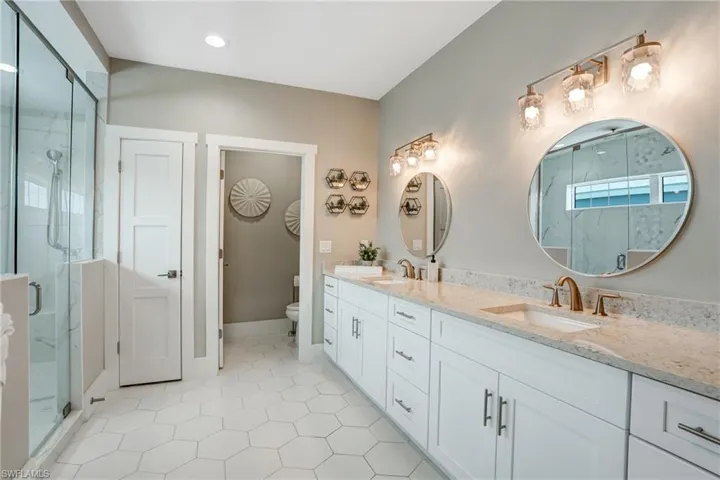 Full bathroom featuring double vanity, a marble finish shower, light tile patterned floors, and recessed lighting - Virtually Edited Image