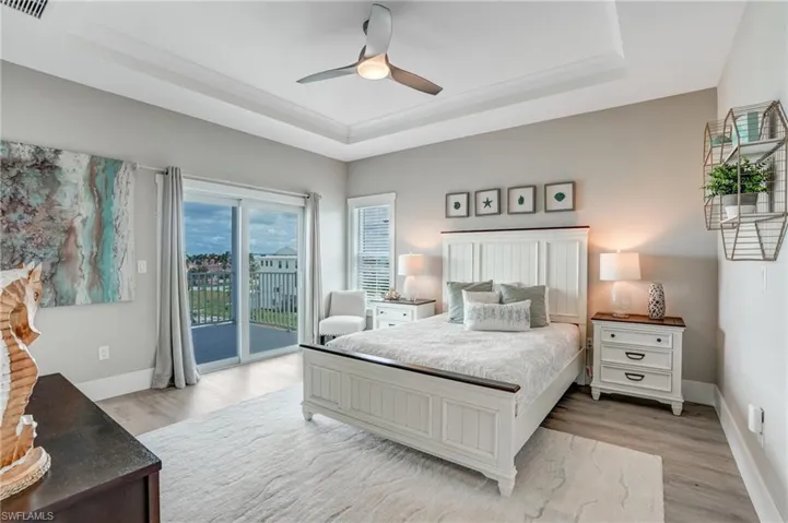 Bedroom featuring a tray ceiling, a ceiling fan, and light wood-type flooring - Virtually Edited Image
