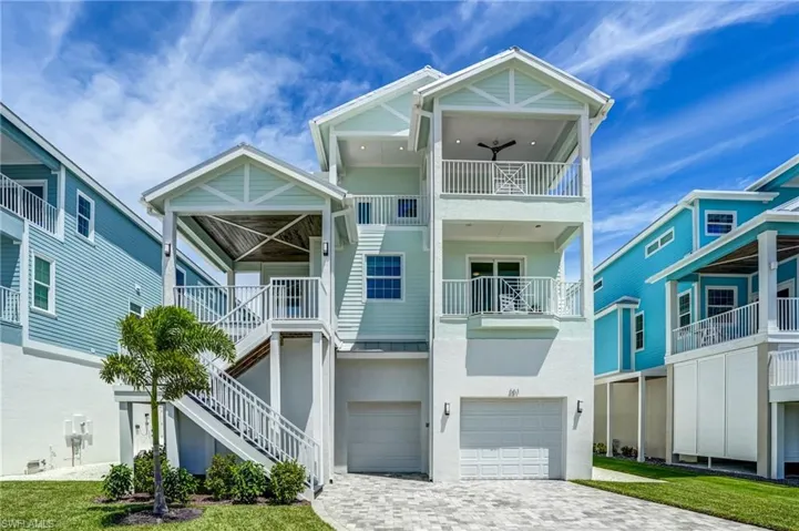 Elevated Coastal home featuring Sunset Decks, decorative driveway, a garage, lots of room for Toys -Virtually Edited Image
