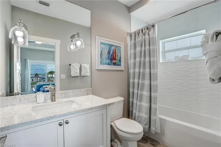 Ensuite bathroom featuring shower / tub combo with curtain, vanity, and wood finished floors - Virtually Edited Image