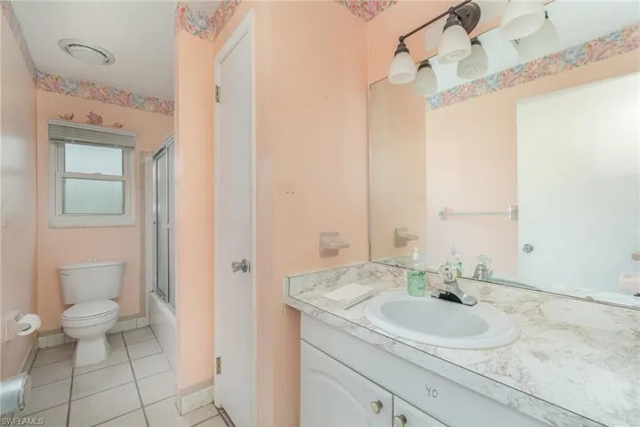 Full bathroom featuring toilet, tile patterned flooring, enclosed tub / shower combo, and vanity