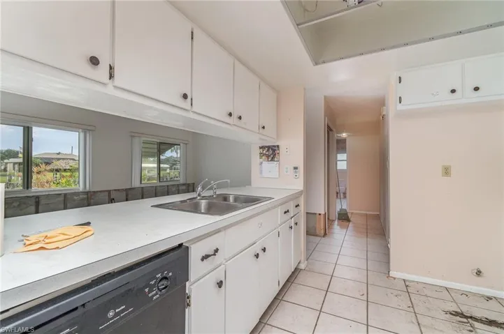 Kitchen with white cabinets, dishwasher, light tile patterned floors, and sink
