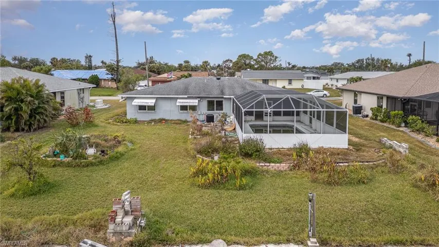 Rear view of property featuring a yard and glass enclosure