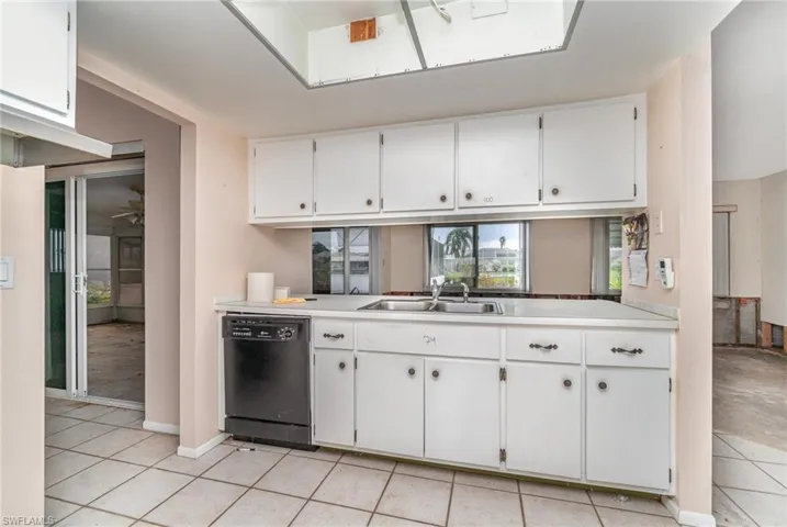 Kitchen with dishwasher, ceiling fan, white cabinetry, light tile patterned flooring, and sink