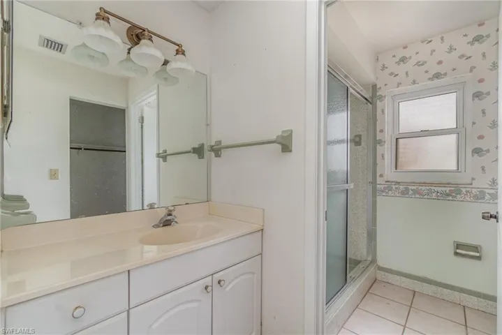 Bathroom featuring vanity, tile patterned floors, and a shower with shower door