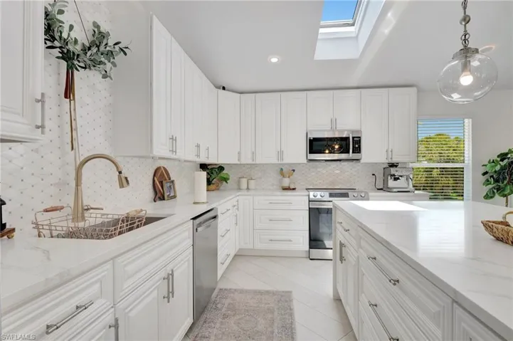 Kitchen featuring a skylight, white cabinets, and stainless steel appliances