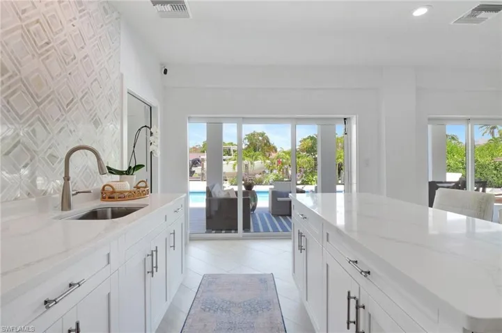 Kitchen featuring light stone countertops, white cabinetry, a center island, and recessed lighting