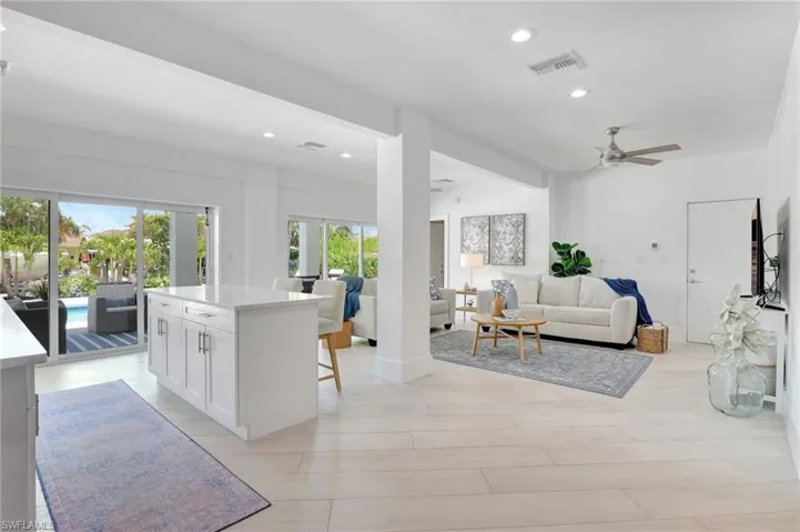 Kitchen with open floor plan, a center island, white cabinets, recessed lighting, and ceiling fan
