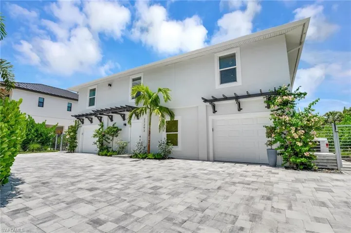 View of front of property with an attached garage, stucco siding, driveway, and a pergola