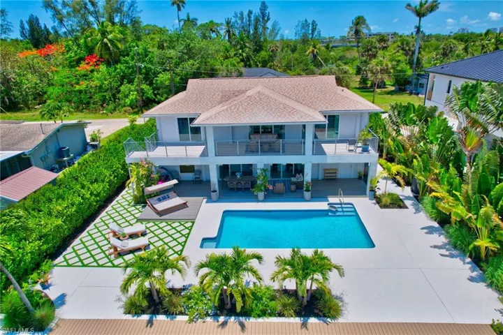 Rear view of property with a patio area, an outdoor pool, a shingled roof, and a balcony