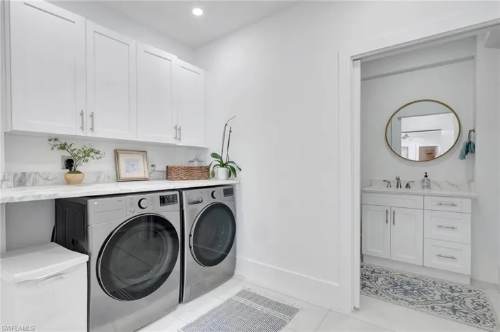 Laundry room featuring cabinet space, washer and clothes dryer, light tile patterned flooring, and recessed lighting