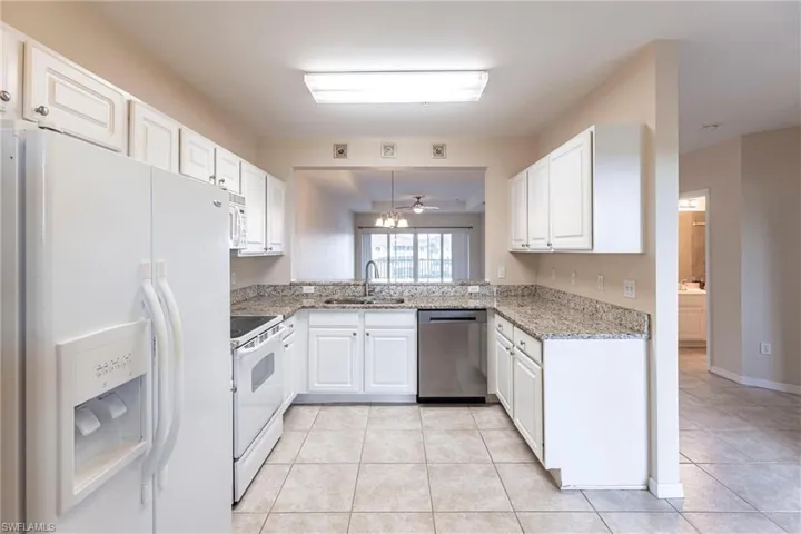 Kitchen featuring white appliances, a sink, white cabinetry, and light tile patterned flooring