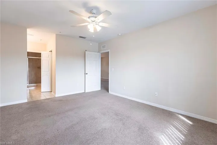 Unfurnished bedroom with light colored carpet, baseboards, and ceiling fan
