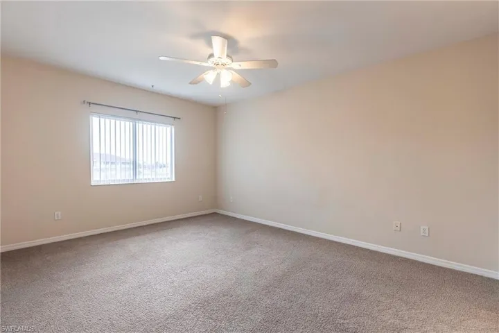 Spare room with a ceiling fan, carpet floors, and baseboards