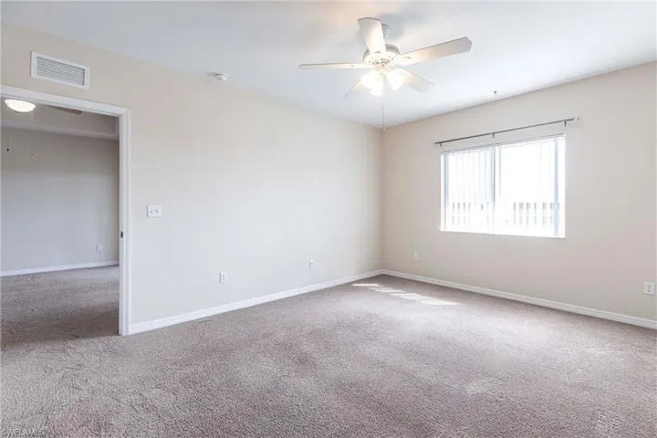 Carpeted spare room with ceiling fan, baseboards, and a smoke detector