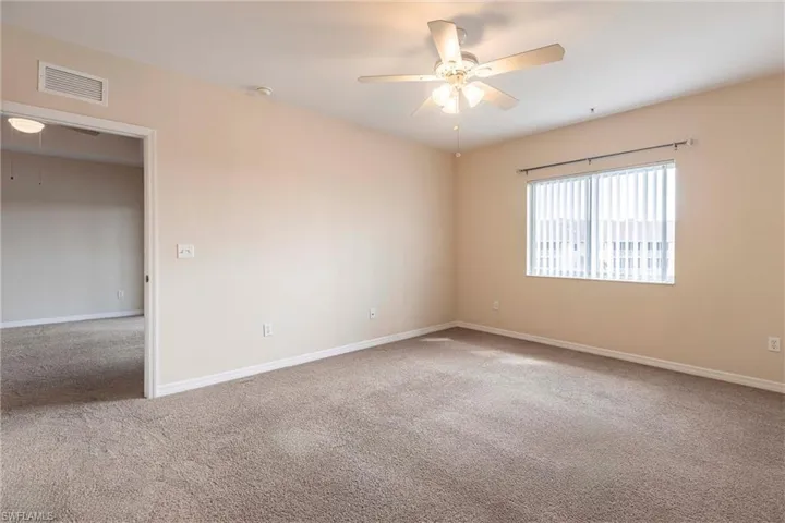 Carpeted empty room featuring ceiling fan, baseboards, and a smoke detector