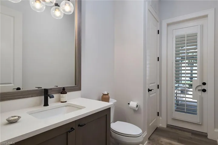 Bathroom with hardwood / wood-style flooring, vanity, a chandelier, and toilet
