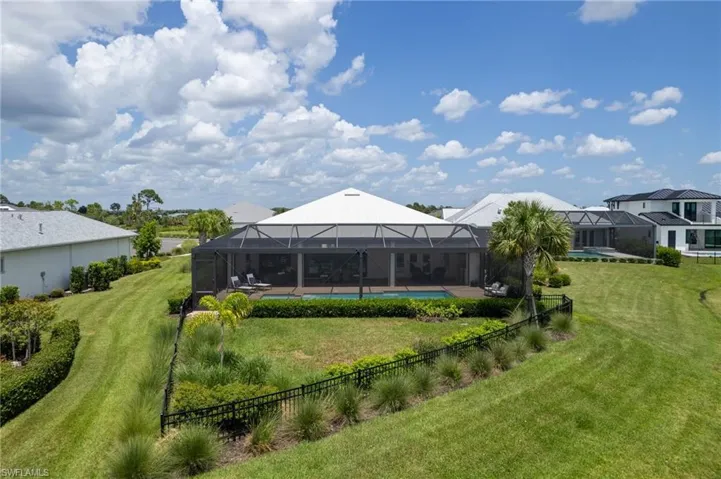 Back of property featuring a swimming pool, glass enclosure, and a lawn