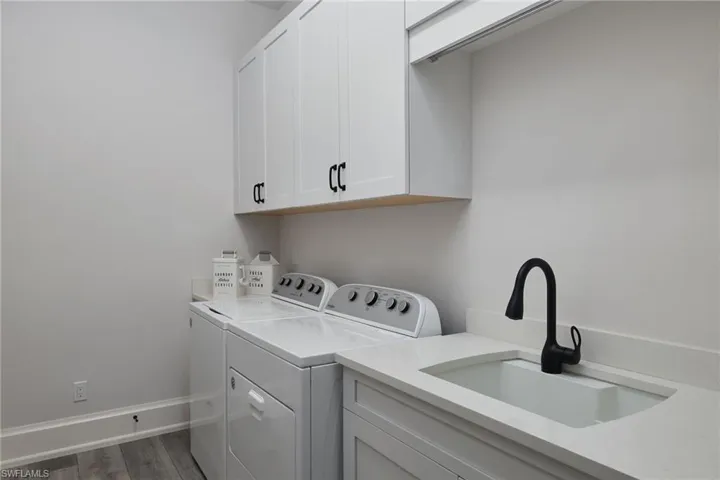 Washroom with washer and dryer, sink, dark wood-type flooring, and cabinets