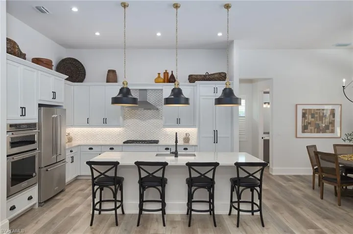 Kitchen featuring light hardwood / wood-style floors, appliances with stainless steel finishes, sink, and wall chimney range hood