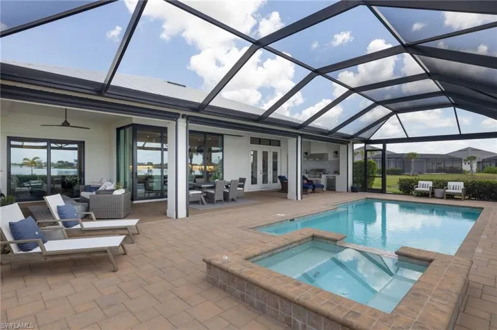 View of pool with an in ground hot tub, glass enclosure, ceiling fan, and a patio area