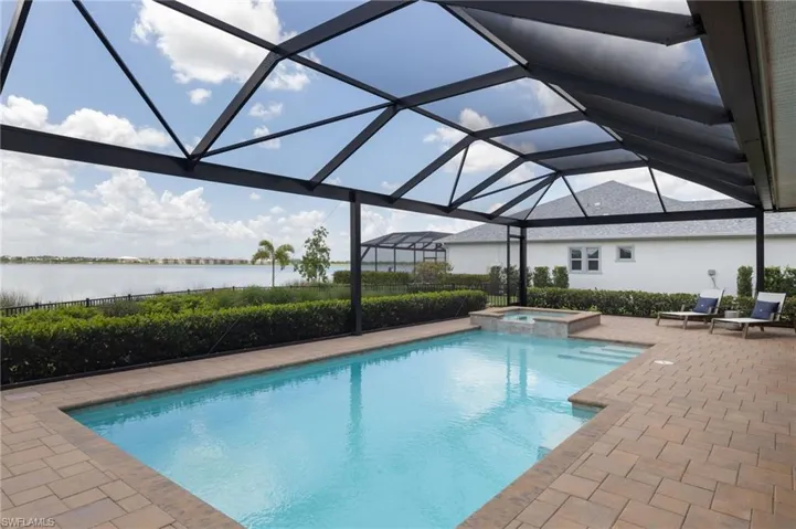 View of swimming pool with glass enclosure, a patio area, and an in ground hot tub