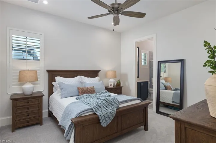 Carpeted bedroom with ceiling fan and ensuite bath