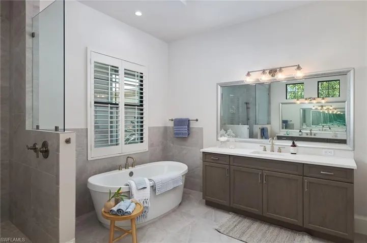 Bathroom featuring tile walls, tile patterned flooring, shower with separate bathtub, and vanity