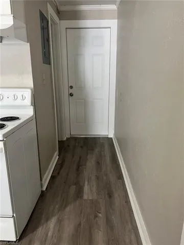 Laundry area with ornamental molding, dark wood finished floors, and electric panel