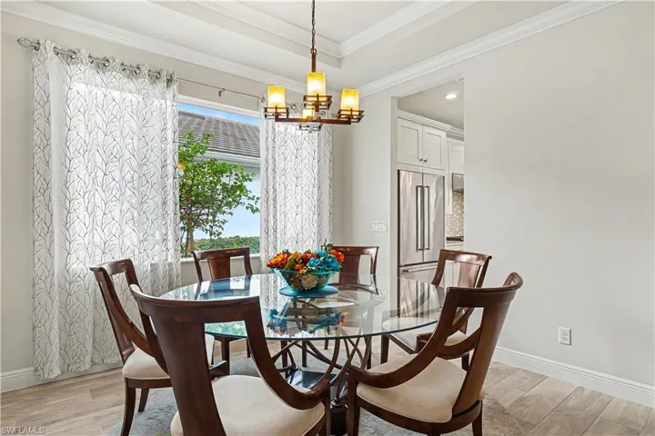 Tray ceiling, crown molding, tile flooring, recessed lighting, and a modern chandelier.