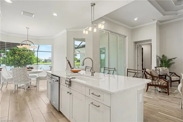 Kitchen island with single granite sink, stainless steel dishwasher, and white cabinetry.