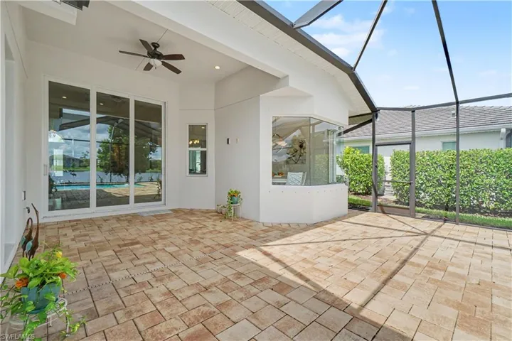 Expansive screened lanai featuring paver flooring, overhead ceiling fan, and large sliding glass doors