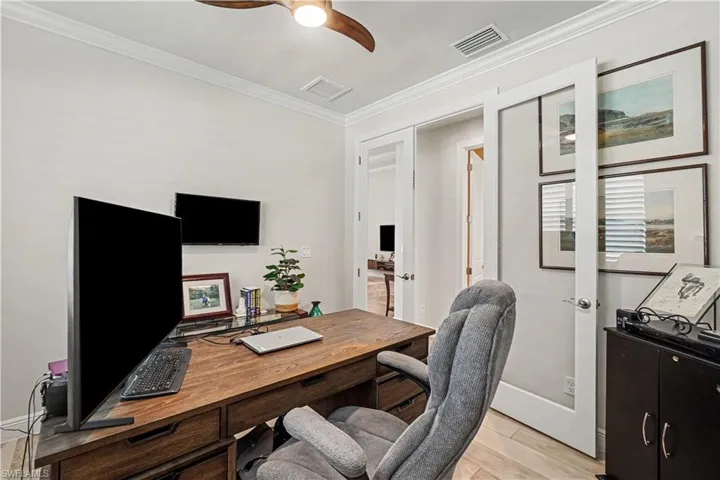 Glass-paneled French doors, crown molding, wood-finish flooring, and a ceiling fan with integrated lighting