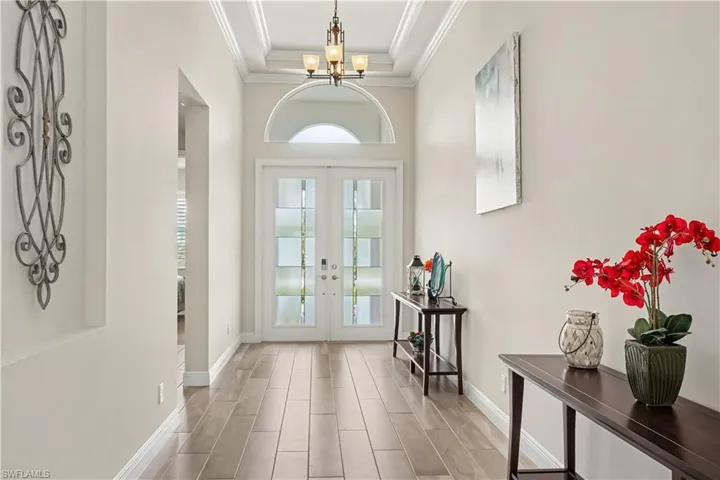 Double entry doors with frosted glass panels, an arched transom, tray ceiling with crown molding.