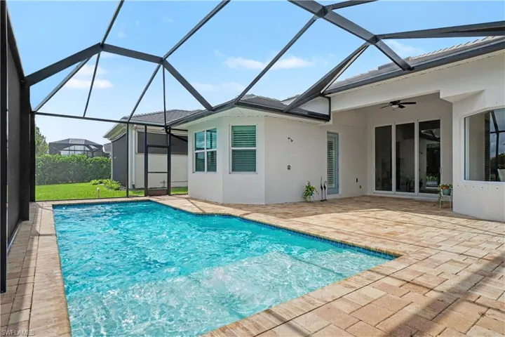 Screened-in outdoor living space featuring a rectangular swimming pool with integrated steps, a paver patio, and large sliding glass doors