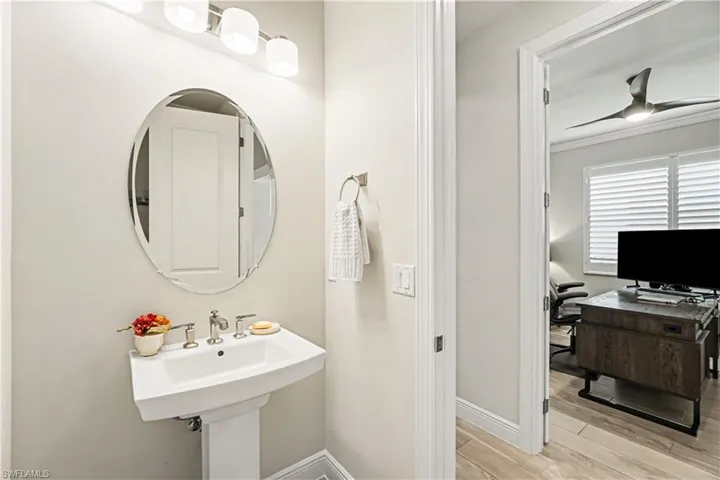Pedestal sink with polished chrome fixtures, oval mirror.