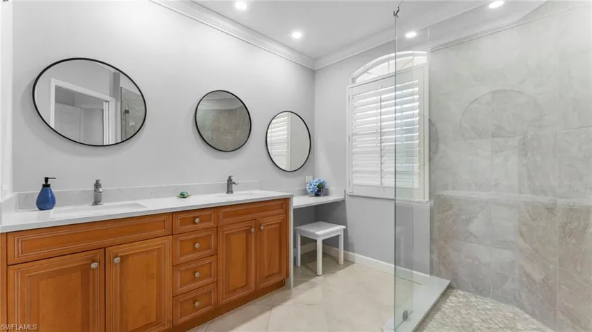 Bathroom featuring tile patterned flooring, crown molding, vanity, and tiled shower