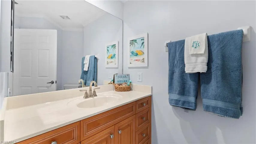 Bathroom with crown molding, vanity, and toilet
